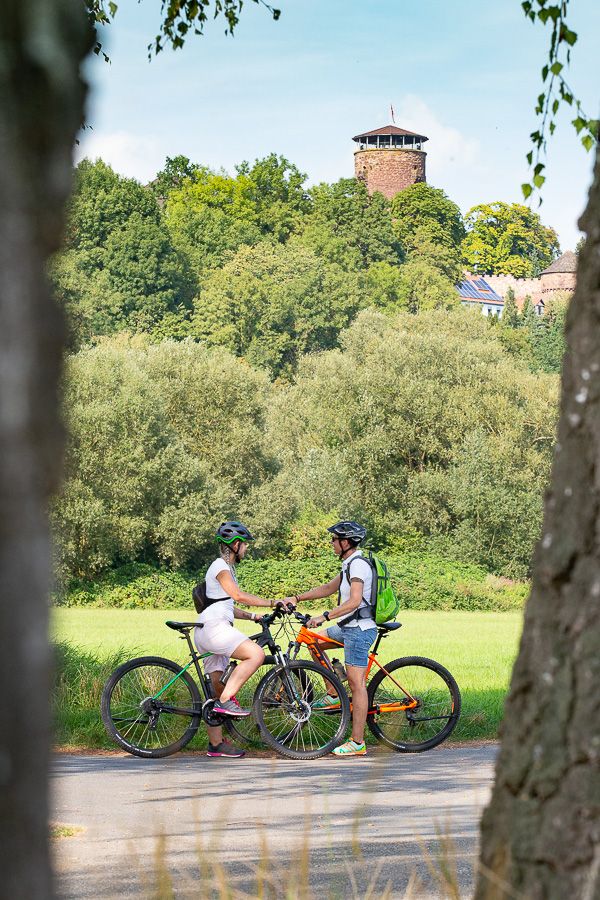 Zwei Radfahrer auf dem Diemelradweg bei Trendelburg, im Hintergrund die Burg Zwei Radfahrer auf dem Diemelradweg bei Trendelburg, im Hintergrund die Burg