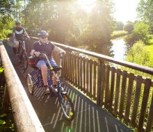 Radfahrer und ein Sesseldreiradfahrer auf der Bruecke &uuml;ber die Diemel bei Warburg