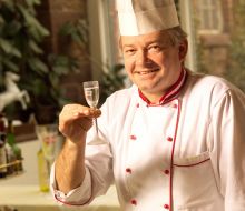 Ein Koch h&auml;lt ein Glas Sekt in die Kamera 