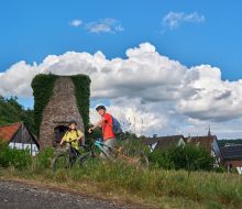 Zwei Radfahrer neben dem Stadtmauerturm in Bad Karlshafen-Helmarshausen