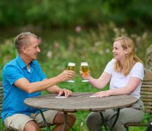 Zwei Personen sitzen an einem Gartentisch und prosten sich zu